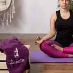 Frau sitzt auf Yoga-Matte und hat ein personalisiertes Handtuch mit Namen und Motiv